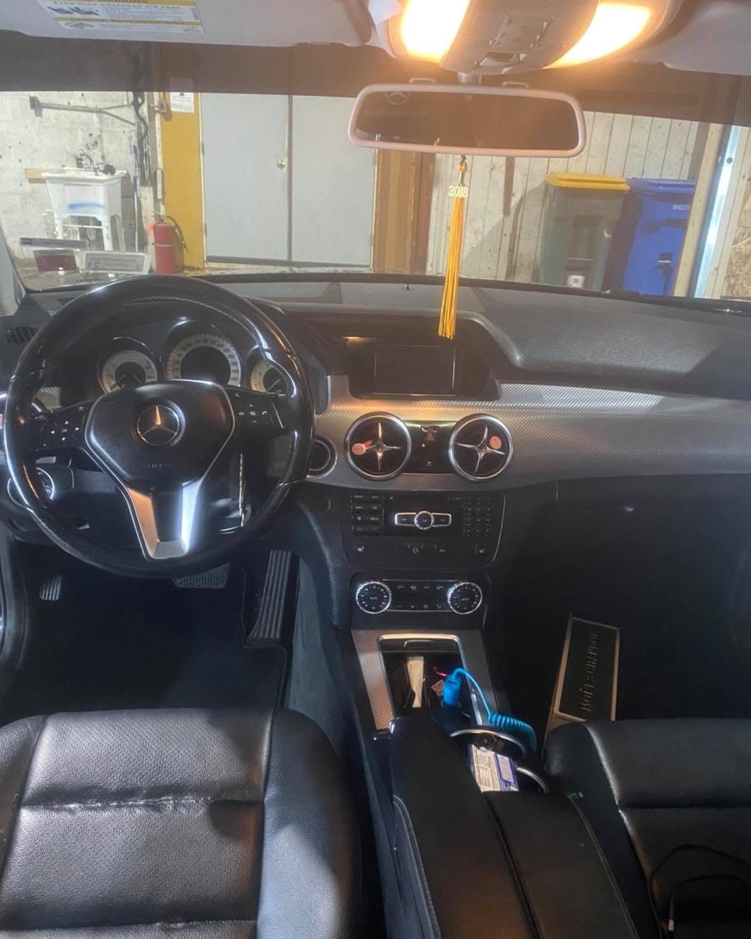 Mercedes-Benz car interior with black steering wheel, dashboard, and leather seats in auto repair shop