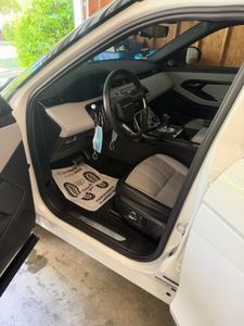 White BMW sedan interior with tan leather seats and dark steering wheel, driver side door open