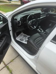 White vintage car interior with black steering wheel and dashboard visible through open door