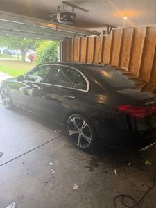 Black sedan parked in garage with wooden wall paneling and natural light from window