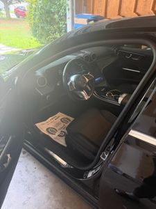 Black car interior with steering wheel and dashboard visible through open driver side door