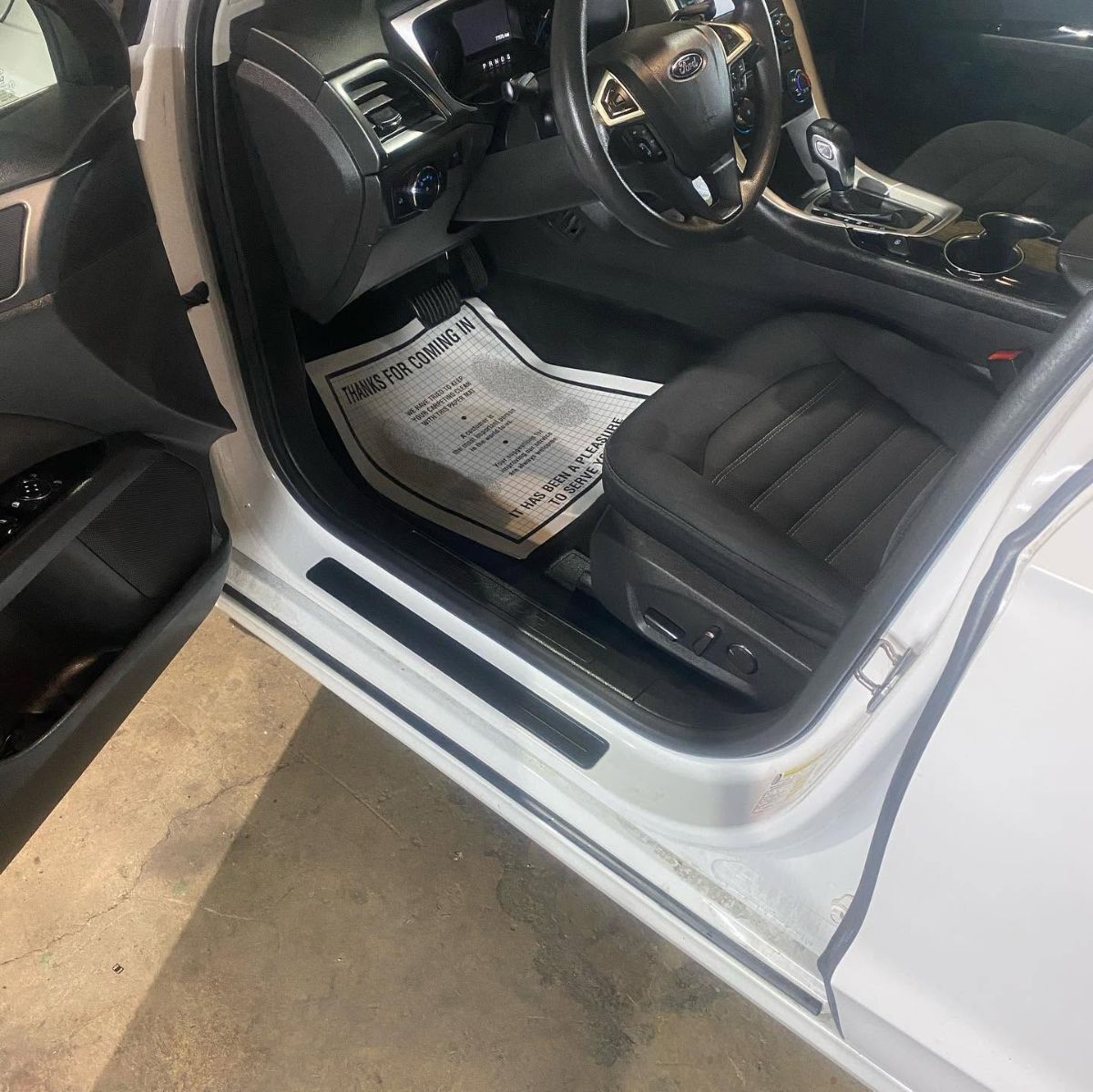 White Ford vehicle interior with black leather seats and steering wheel visible